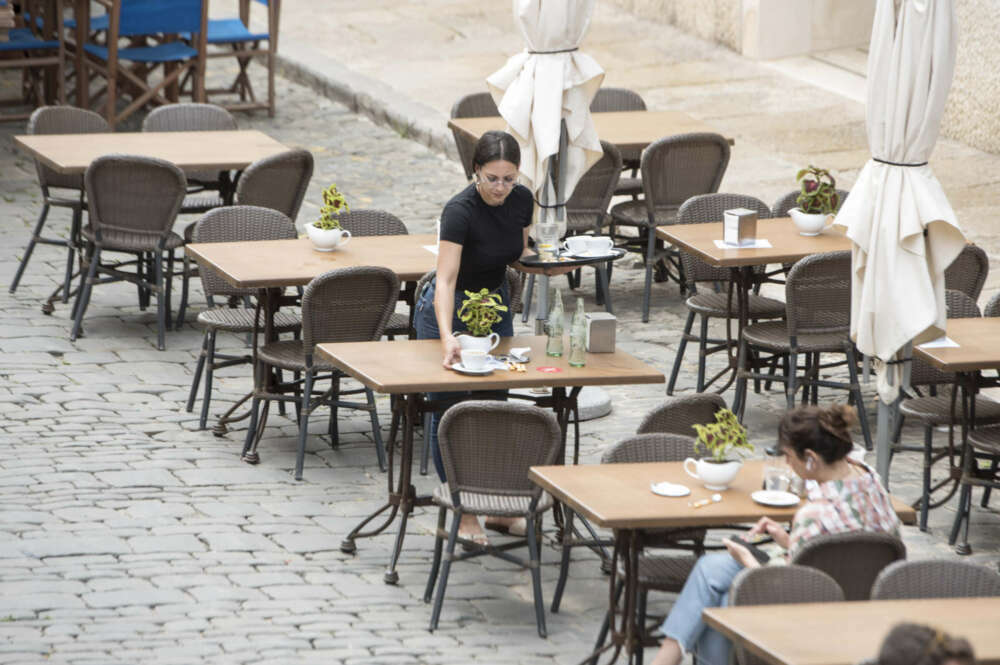 MAHÓN (MENORCA), 23/05/2022.- Una trabajadora recoge una mesa este lunes en la ciudad balear de Mahón. Según la empresa de recursos humanos Randstad, Baleares es la zona con más ofertas en la hostelería. EFE/ David Arquimbau Sintes