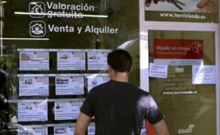 Un joven mira un escaparate con anuncios de venta y alquiler en una inmobiliaria. / EFE