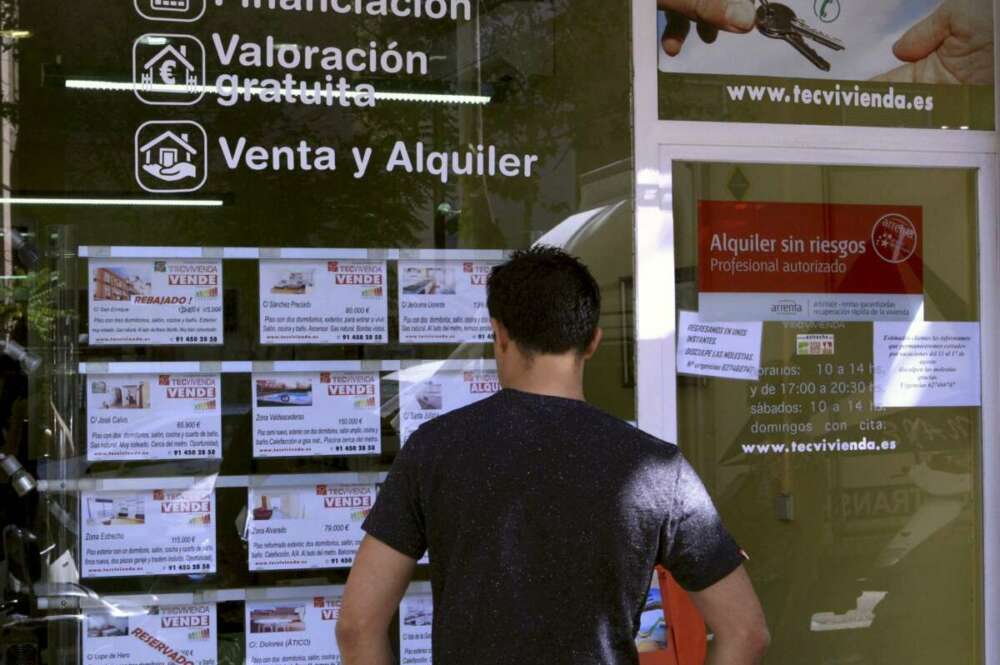 Un joven mira un escaparate con anuncios de venta y alquiler en una inmobiliaria. / EFE