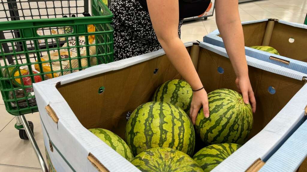 Una persona coge una sandía en un supermercado.