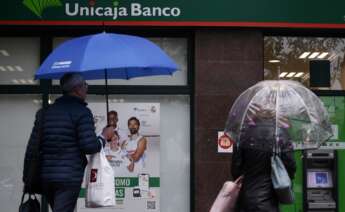 Una mujer saca dinero de un Unicaja Banco.