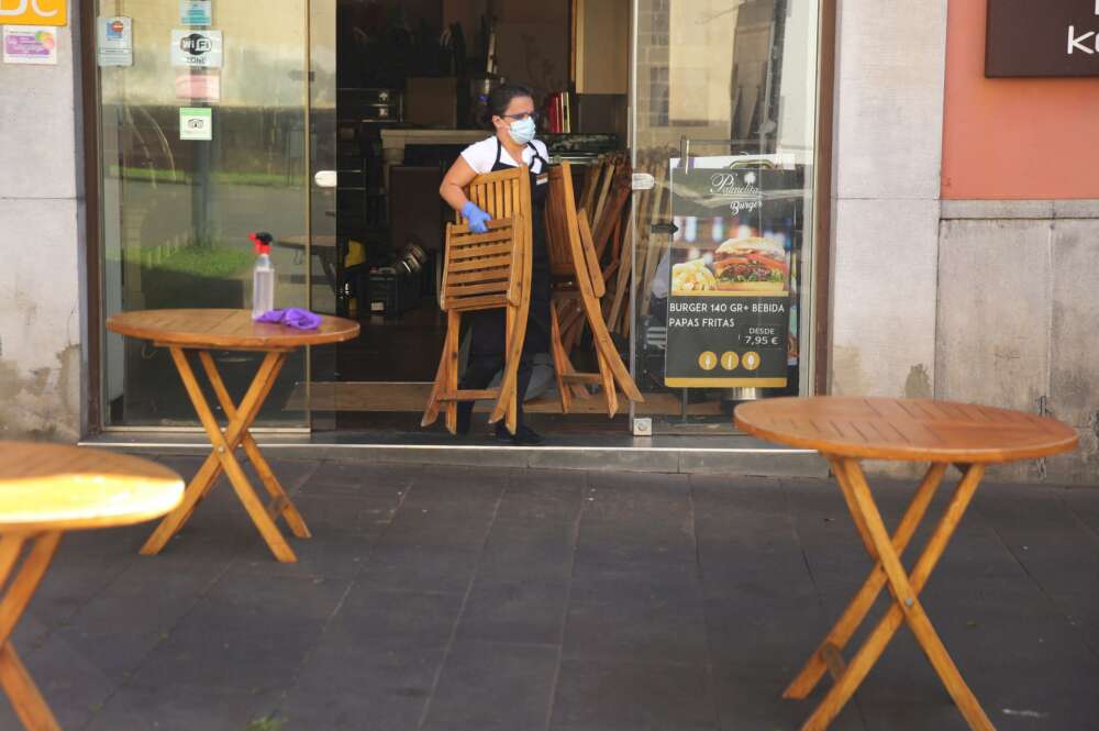 Una trabajadora de un establecimiento de hostelería saca las sillas a la terraza.