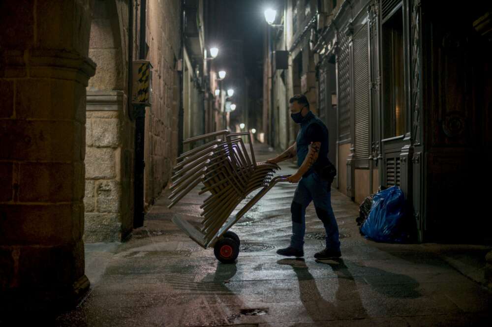 Un hombre recoge las sillas de una terraza / EFE