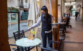 Una camarera desinfecta una mesa