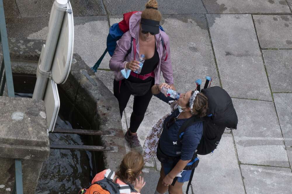 Tres peregrinas beben agua en una fuente en Santiago de Compostela