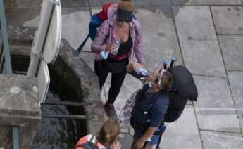 Tres peregrinas beben agua en una fuente en Santiago de Compostela