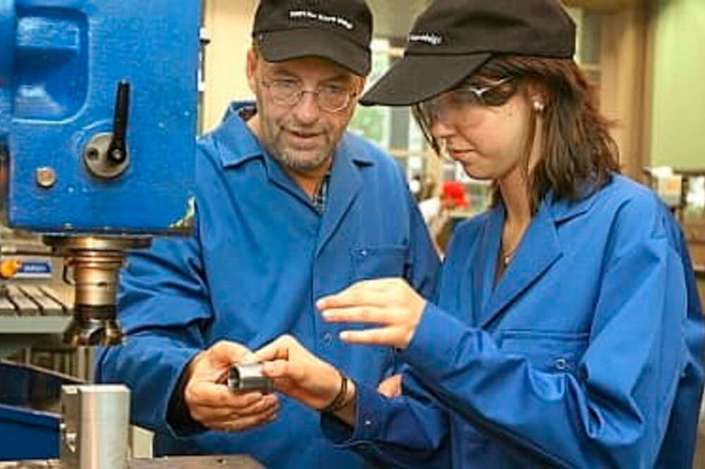 Trabajadores manejando una máquina industrial - INE