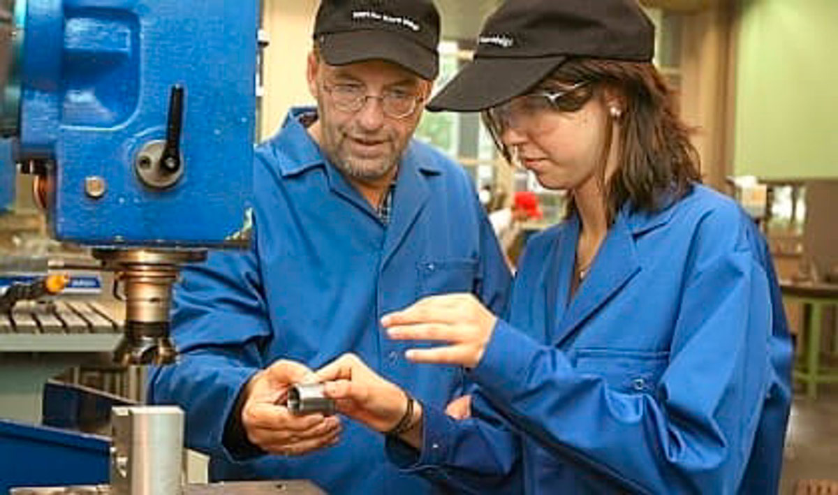 Trabajadores manejando una máquina industrial - INE