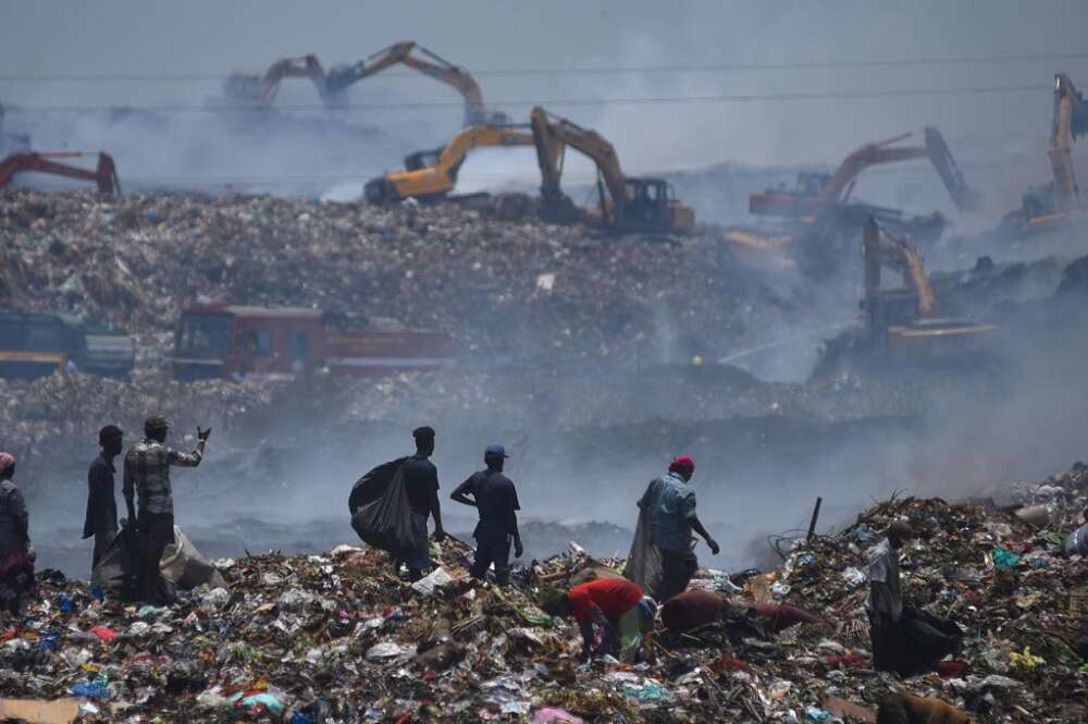 Los denominados 'rebuscadores' de la basura observan cómo el humo sale del vertedero de Perungudi después de que eun gran incendio un par de días antes, en Chennai, India, el 29 de abril de 2022