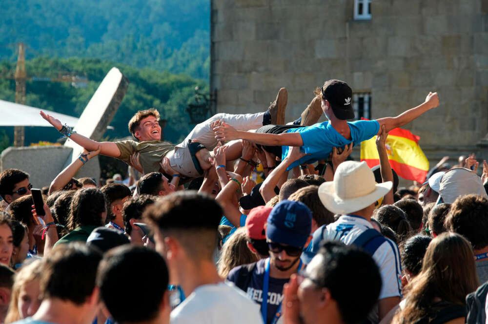 Dos jóvenes son levantados en brazos durante la inauguración y acto de acogida de la peregrinación europea de jóvenes 2022, en el Obradoiro de Santiago