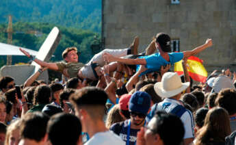 Dos jóvenes son levantados en brazos durante la inauguración y acto de acogida de la peregrinación europea de jóvenes 2022, en el Obradoiro de Santiago