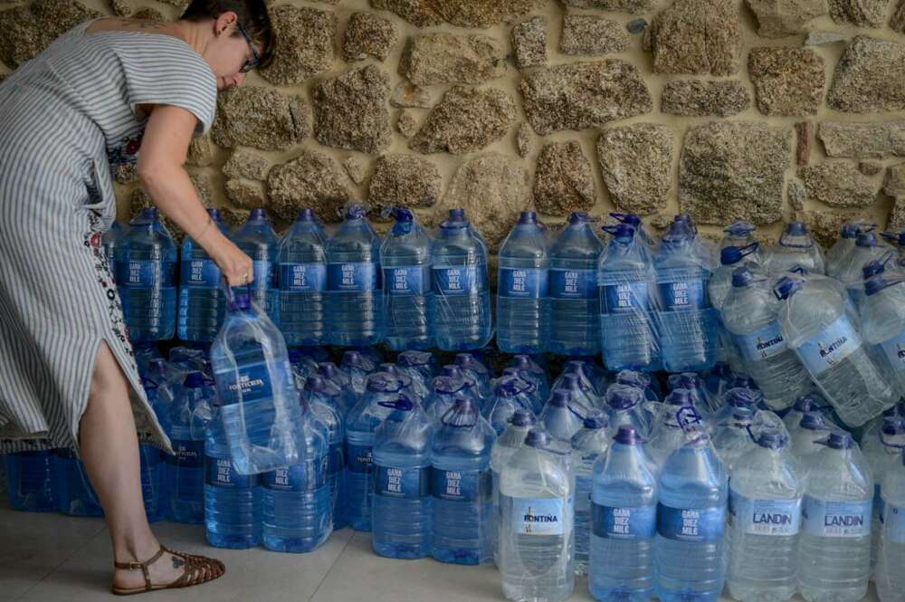 Una mujer coge una botella de agua embotellada en el local que el Gobierno local de Ribadavia ha habilitado para que se abastezcan los vecinos más afectados por los cortes de suministro