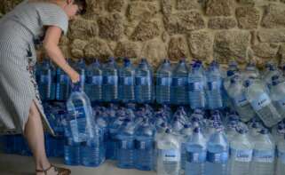 Una mujer coge una botella de agua embotellada en el local que el Gobierno local de Ribadavia ha habilitado para que se abastezcan los vecinos más afectados por los cortes de suministro