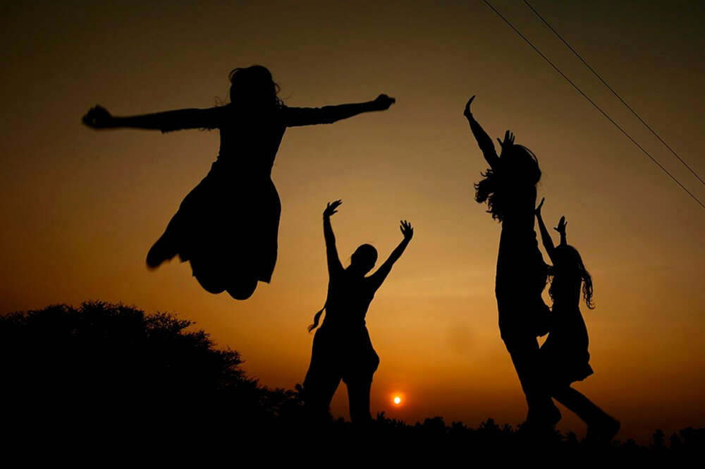 Unos jóvenes saltan durante un atardecer