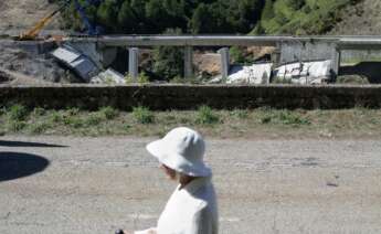 Una mujer camina por la carretera mientras se realiza el desmontaje de las pilas 1 y 2 del viaducto de O Castro, en el kilómetro 430 sentido A Coruña de la autovía A-6. - Carlos Castro -