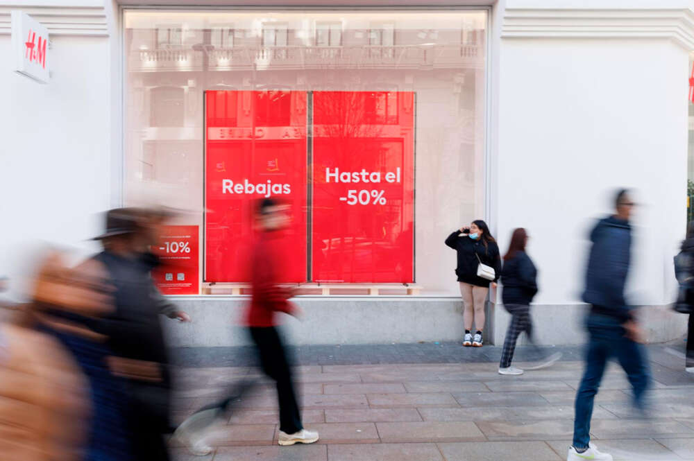 Varias personas caminan frente a una tienda de H&M con el cartel de rebajas