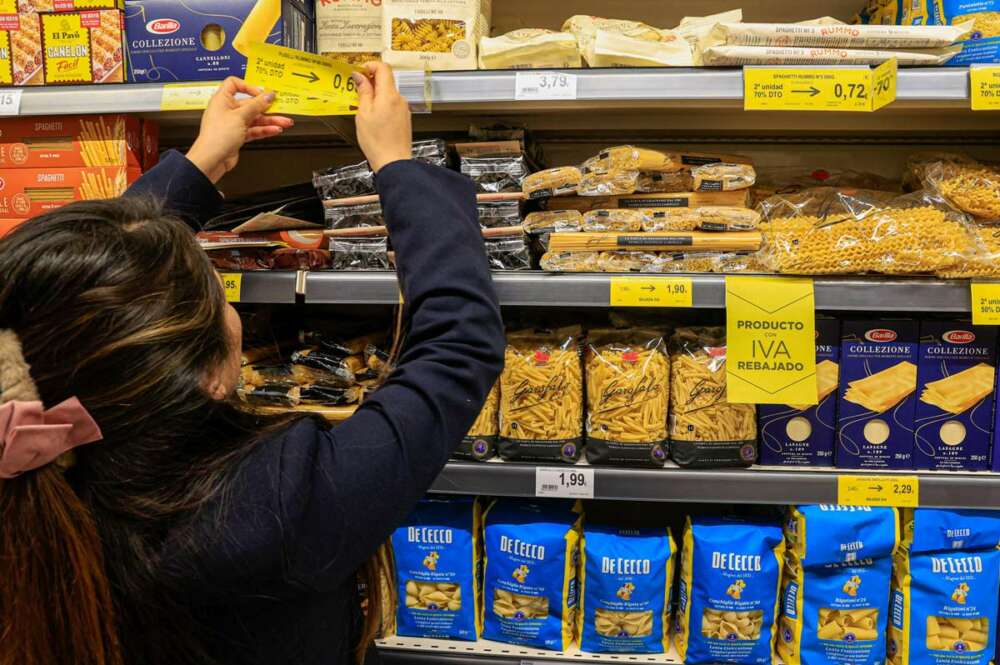 Una empleada de un supermercado coloca los carteles con precios.