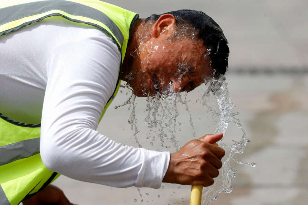 Un trabajador se refresca con una manguera en una calle de Madrid. España atraviesa estos días la que es, de momento, su peor ola de calor del verano
