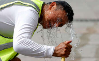 Un trabajador se refresca con una manguera en una calle de Madrid. España atraviesa estos días la que es, de momento, su peor ola de calor del verano