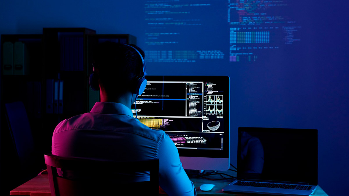 imagen de persona de espaldas sentada frente a un ordenador trabajando en un desarrollo de software