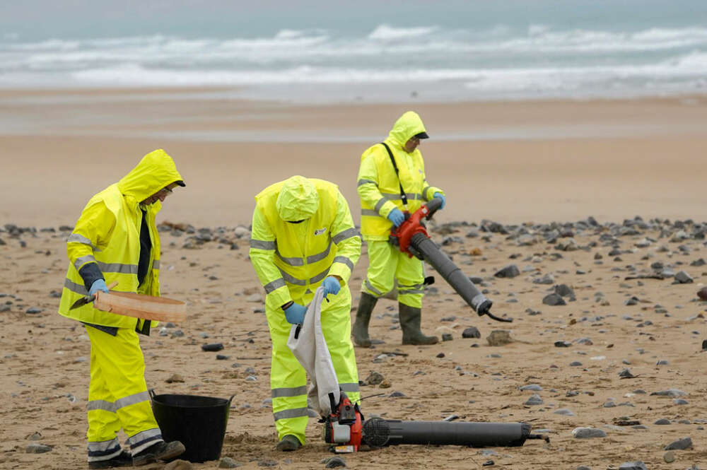 Operarios limpiando la playa de Vega (Asturias)