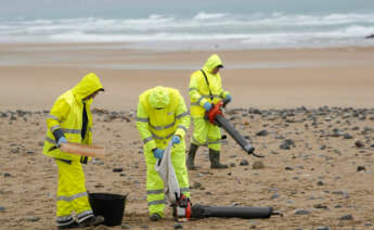 Operarios limpiando la playa de Vega (Asturias)