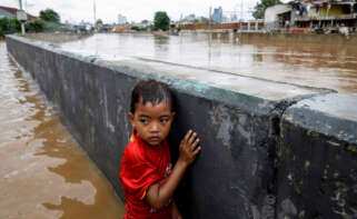 Un niño se protege tras un muro en una carretera inundada de Yakarta (Indonesia) en 2020