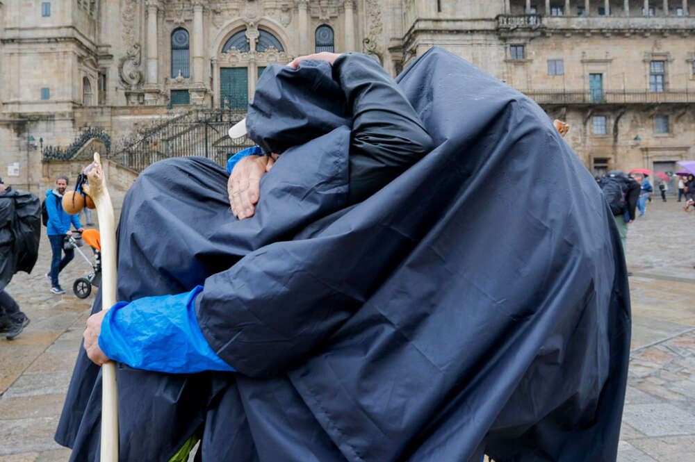 Dos peregrinos se felicitan al concluir el Camino bajo la lluvia