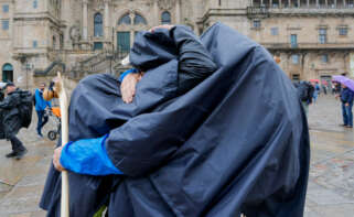 Dos peregrinos se felicitan al concluir el Camino bajo la lluvia