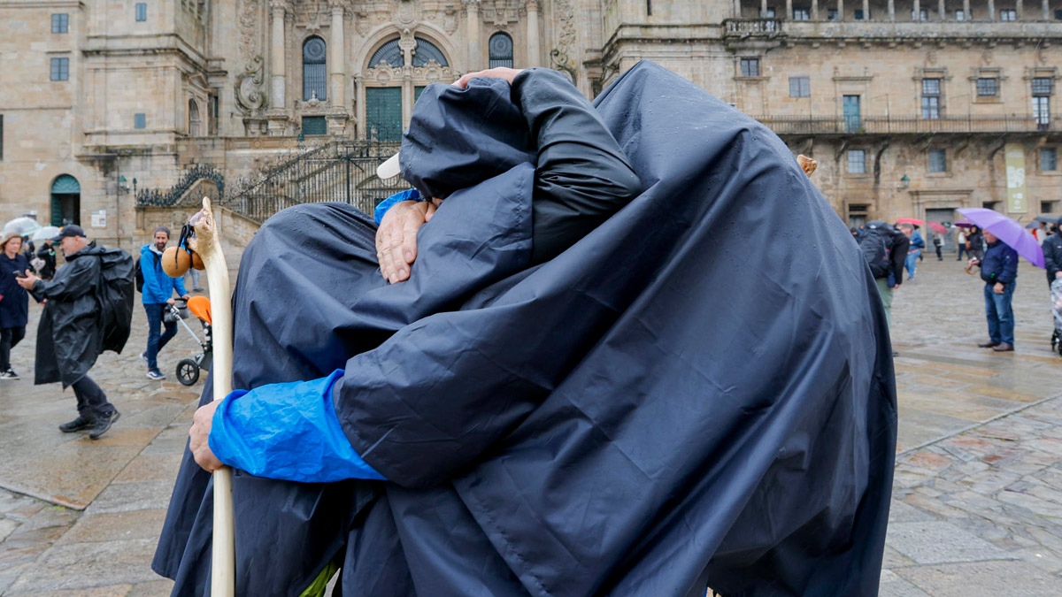 Dos peregrinos se felicitan al concluir el Camino bajo la lluvia