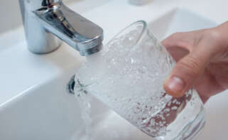 Una persona llena un vaso de agua de un grifo