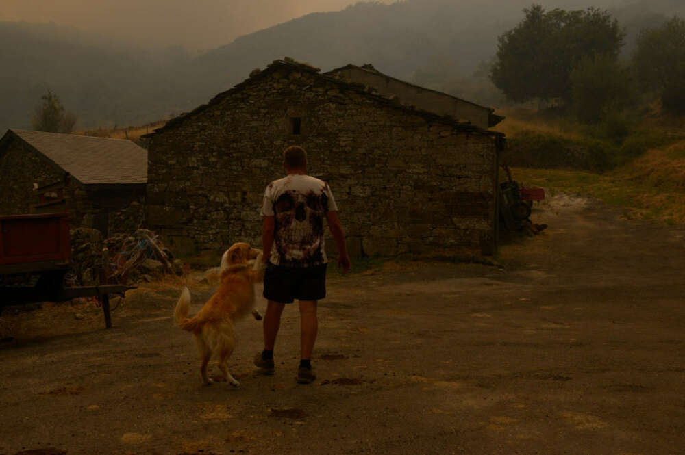 Una persona con su perro observa el incendio en Requeixo, a 11 de agosto de 2025, en Chandrexa de Queixa