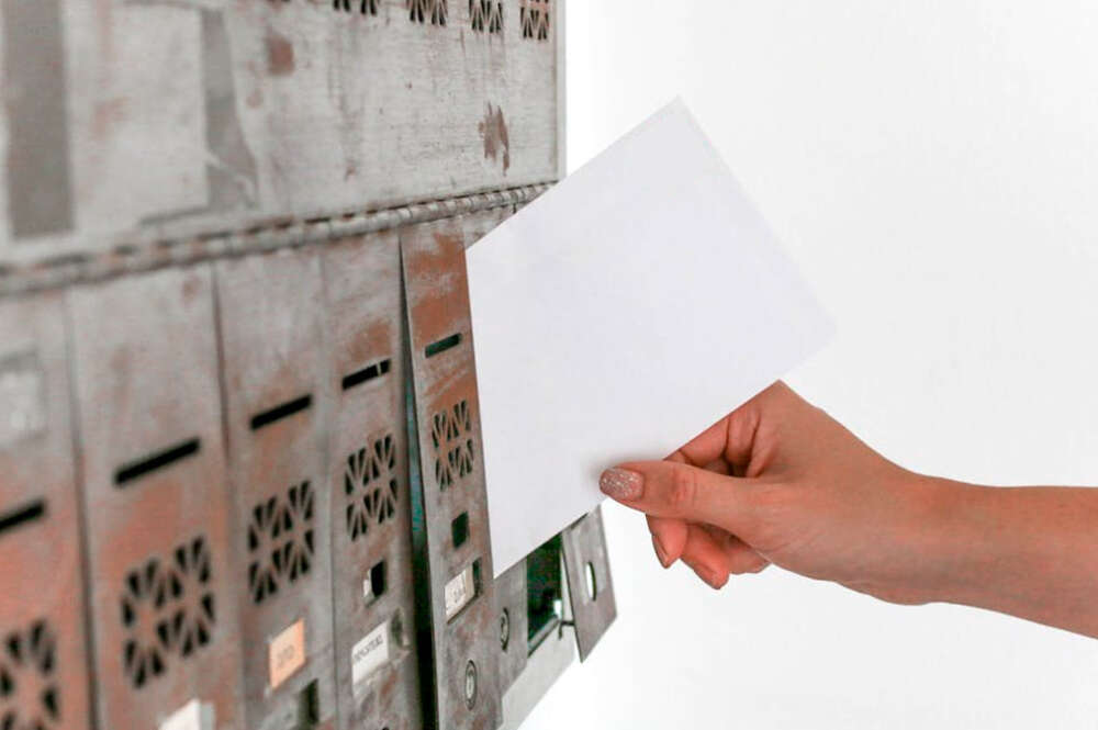 persona metiendo una carta en el buzón de una casa