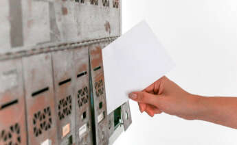 persona metiendo una carta en el buzón de una casa