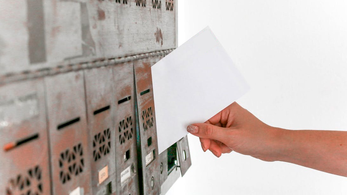 persona metiendo una carta en el buzón de una casa