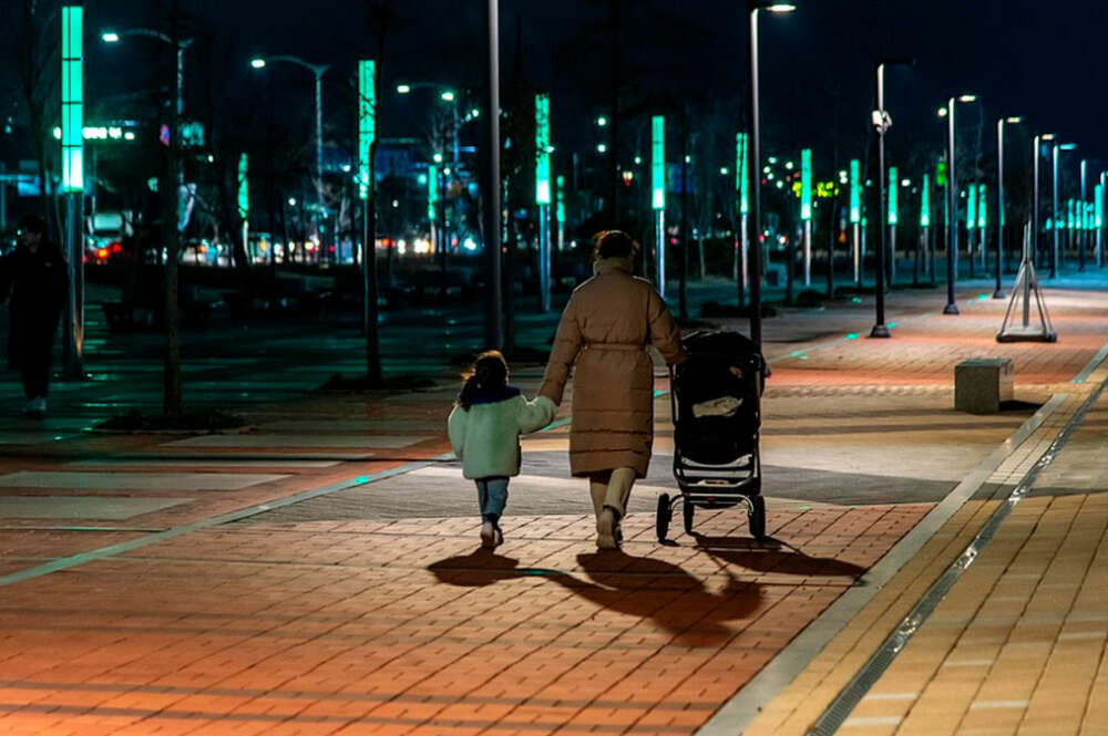 Mujer paseando por la noche con su hija de la mano