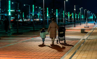 Mujer paseando por la noche con su hija de la mano