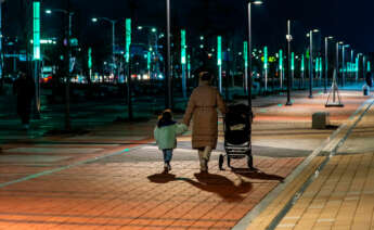 Mujer paseando por la noche con su hija de la mano