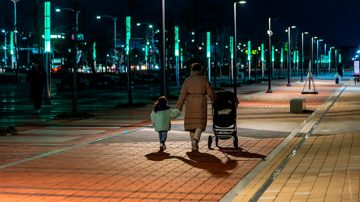 Mujer paseando por la noche con su hija de la mano