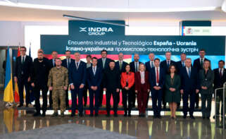 El presidente de Ucrania, Volodímir Zelenski (centro), junto a la ministra de Defensa, Margarita Robles, en la sede de Indra en el marco del encuentro con 13 empresas del sector de la defensa española