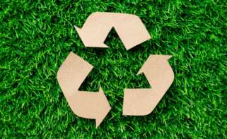 logo de reciclaje hecho con cartón sobre el césped