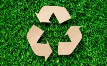 logo de reciclaje hecho con cartón sobre el césped