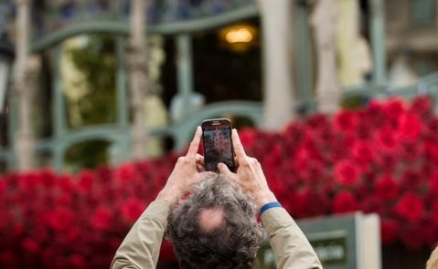 Un turista toma una foto de la Casa Batlló, llena de flores por Sant Jordi