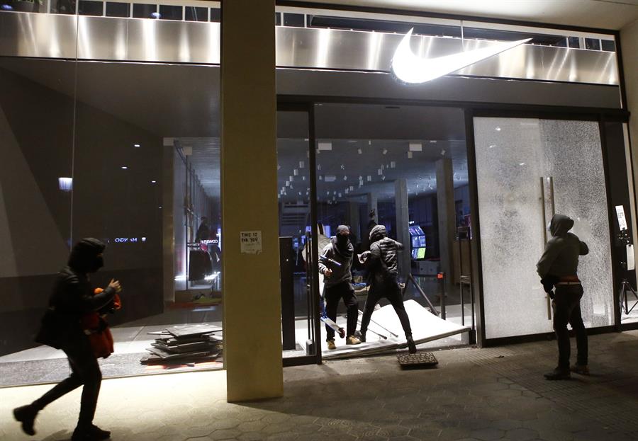 Varios encapuchados entran en un comercio de Barcelona tras la manifestación celebrada esta tarde en protesta por el encarcelamiento del rapero Pablo Hasél. EFE/Quique García