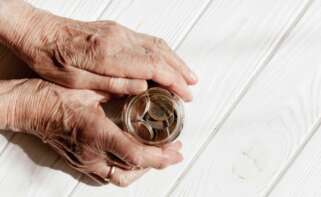 Una anciana coge un frasco con monedas. Foto: Freepik.