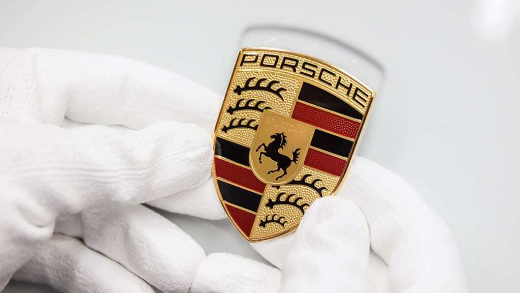 Insignia de Porsche a punto de ser colocada en el capó de un Porsche 911 992.