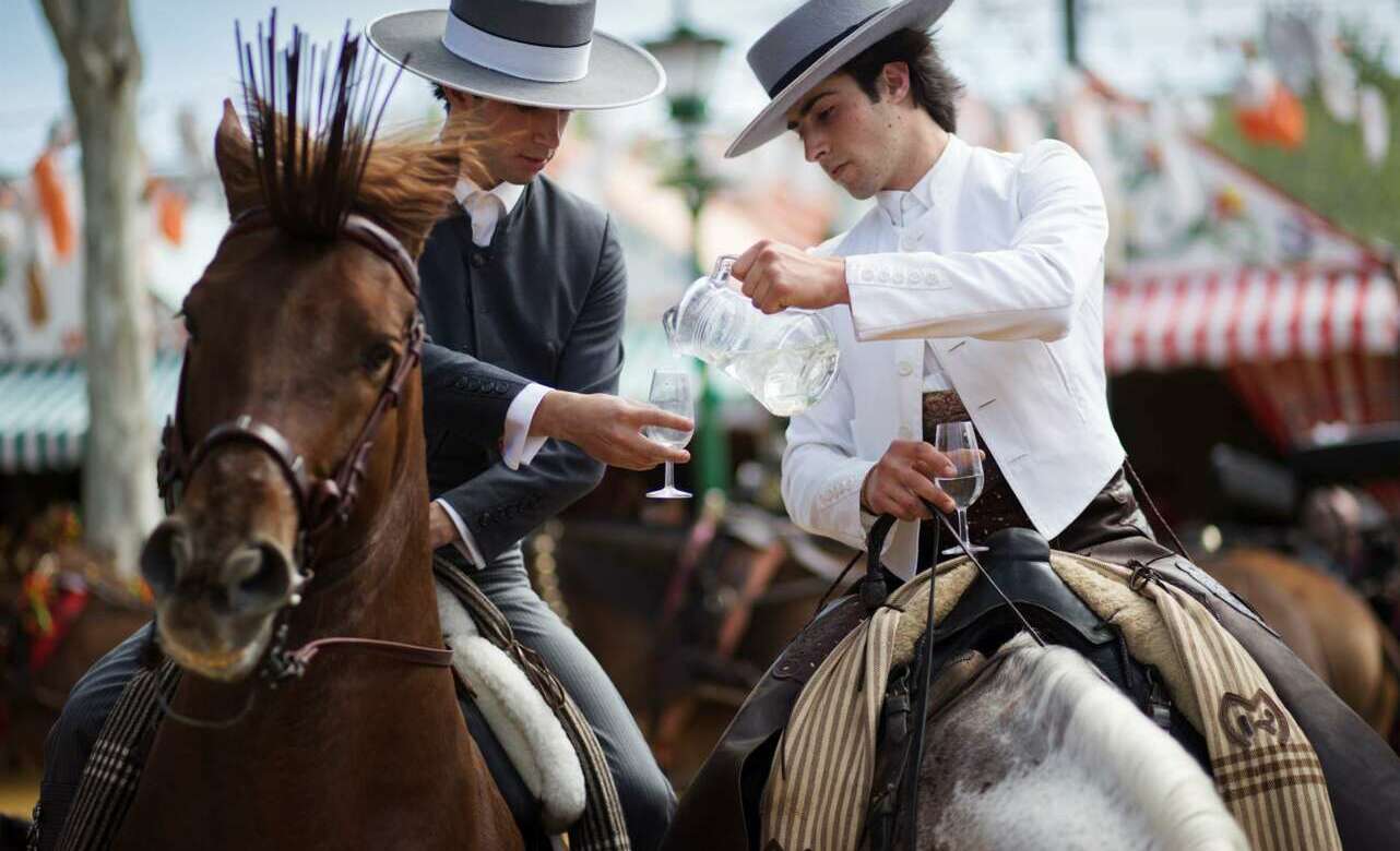 Dos personas a caballo bebiendo rebujito