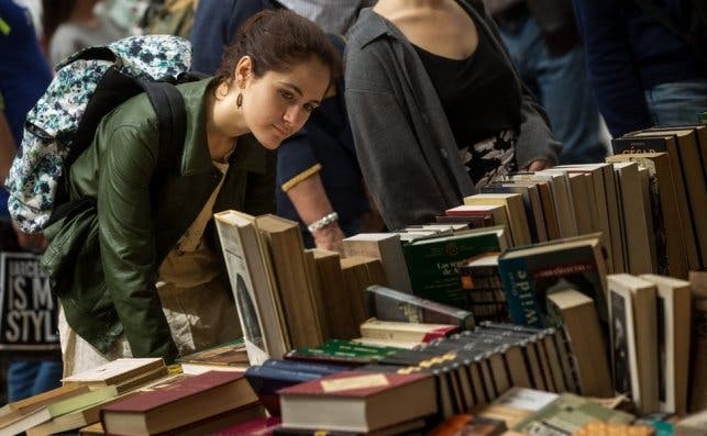 Una joven entre libros en una de las paradas de las Ramblas de Barcelona durante la diada de Sant Jordi / EFE