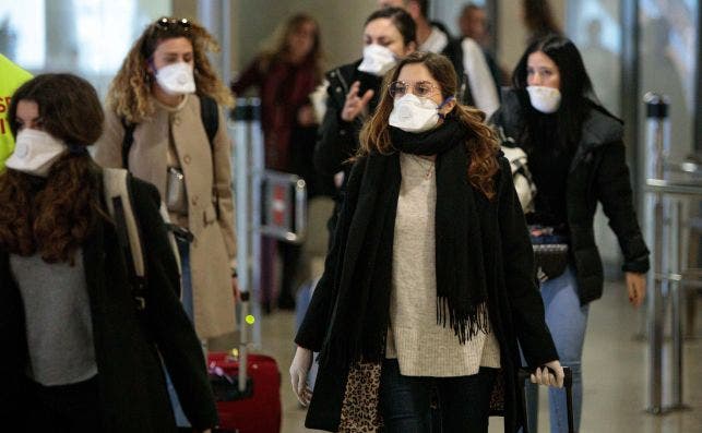 Viajeros procedentes de Italia protegidos con mascarillas por el coronavirus. Foto: EFE