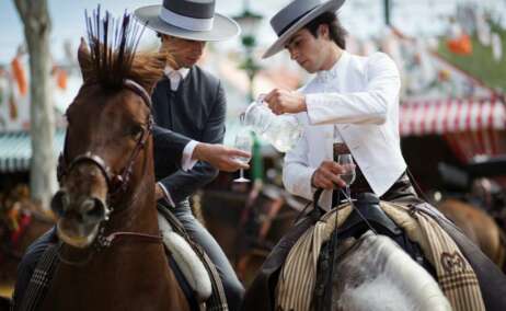 Dos personas a caballo bebiendo rebujito